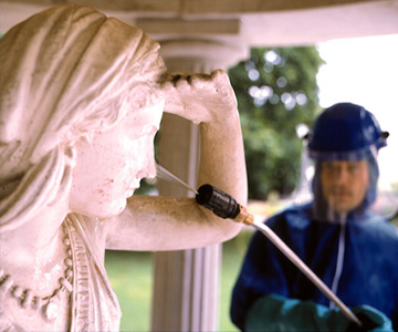 Reinigung einer verwitterten Statue im Außenbereich mit Hochdruckreiniger.