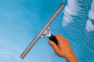 Hand reinigt Glasfläche mit Fensterabzieher vor blauem Himmel.