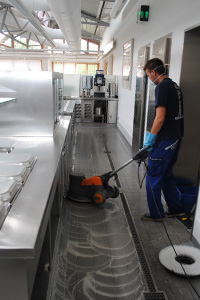 Korrekt-Mitarbeiter reinigt langen Bodenflur mit Bodenreinigungsmaschine.