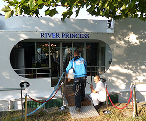 Reinigungsteam säubert den Zugang zum Schiff „River Princess“ mit Schlauch.