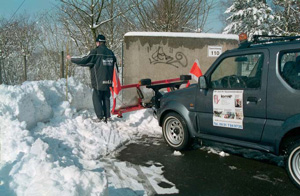 Mann räumt Schnee mit Schneefräse von Zufahrt oder Gehweg.